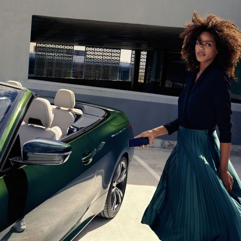 BMW 4 Series Convertible G23 2020 partial side view with a woman using digital key on smartphone BMW 4 Series Convertible G23 2020 San Remo Green metallic partial side view with a woman using digital key on smartphone