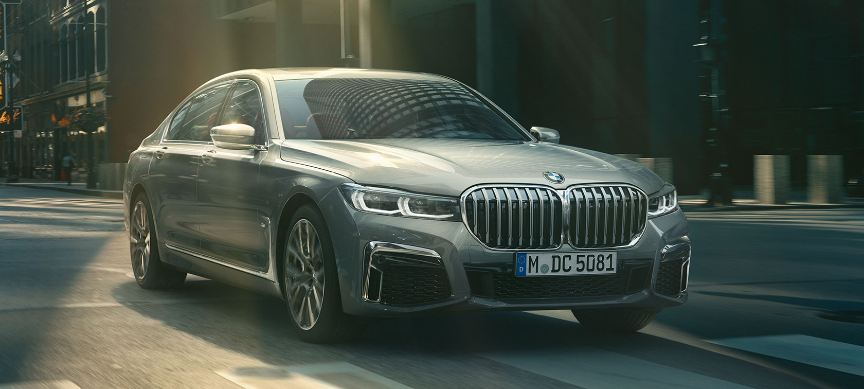 Grey BMW 7 Series Saloon driving, three-quarter front view Grey BMW 7 Series Saloon drives through the urban setting in the three-quarter front view