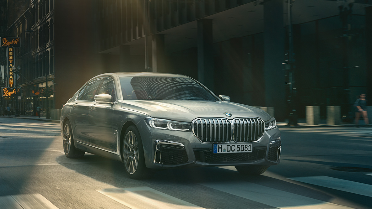 BMW 7 Series Saloon Driving Assistant Professional Driving Assistant Professional: three-quarter front view of BMW 7 Series Saloon driving in front of urban setting