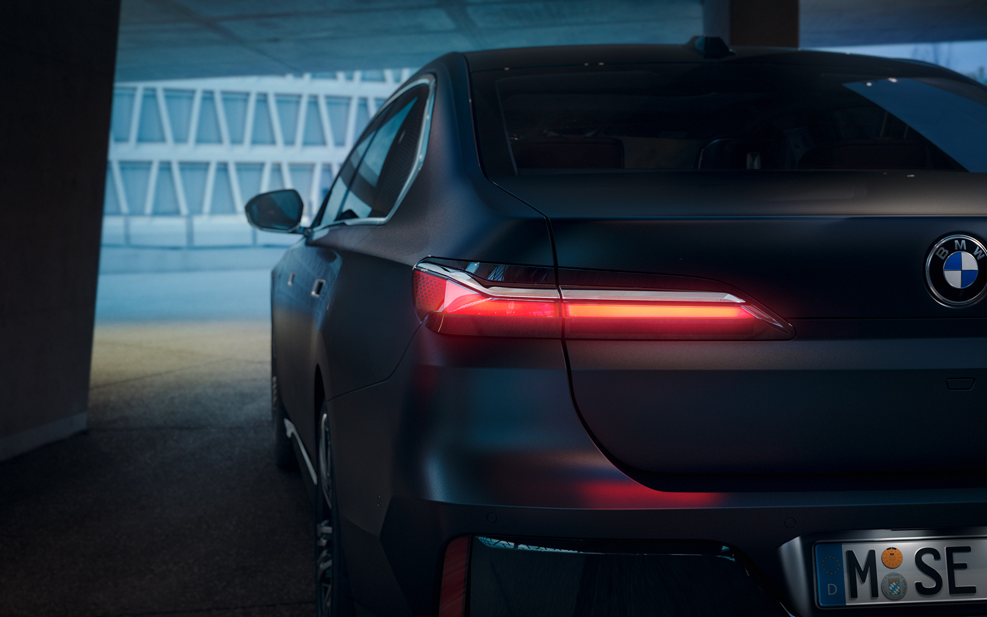 BMW 7 Series Saloon G70 ICE 740i M sports package Frozen Deep Grey metallic rear view with red glowing taillight in tunnel