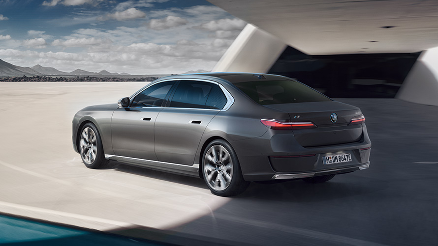 BMW i7 Saloon G70 BMW Individual Oxid grey metallic 3/4 rear view standing in front of building BMW i7 Saloon package 3/4 rear view