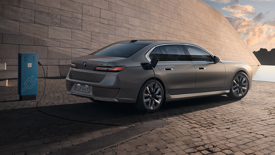 BMW i7 Saloon G70 BMW Individual Oxid grey metallic 3/4 side view from rear at charging station