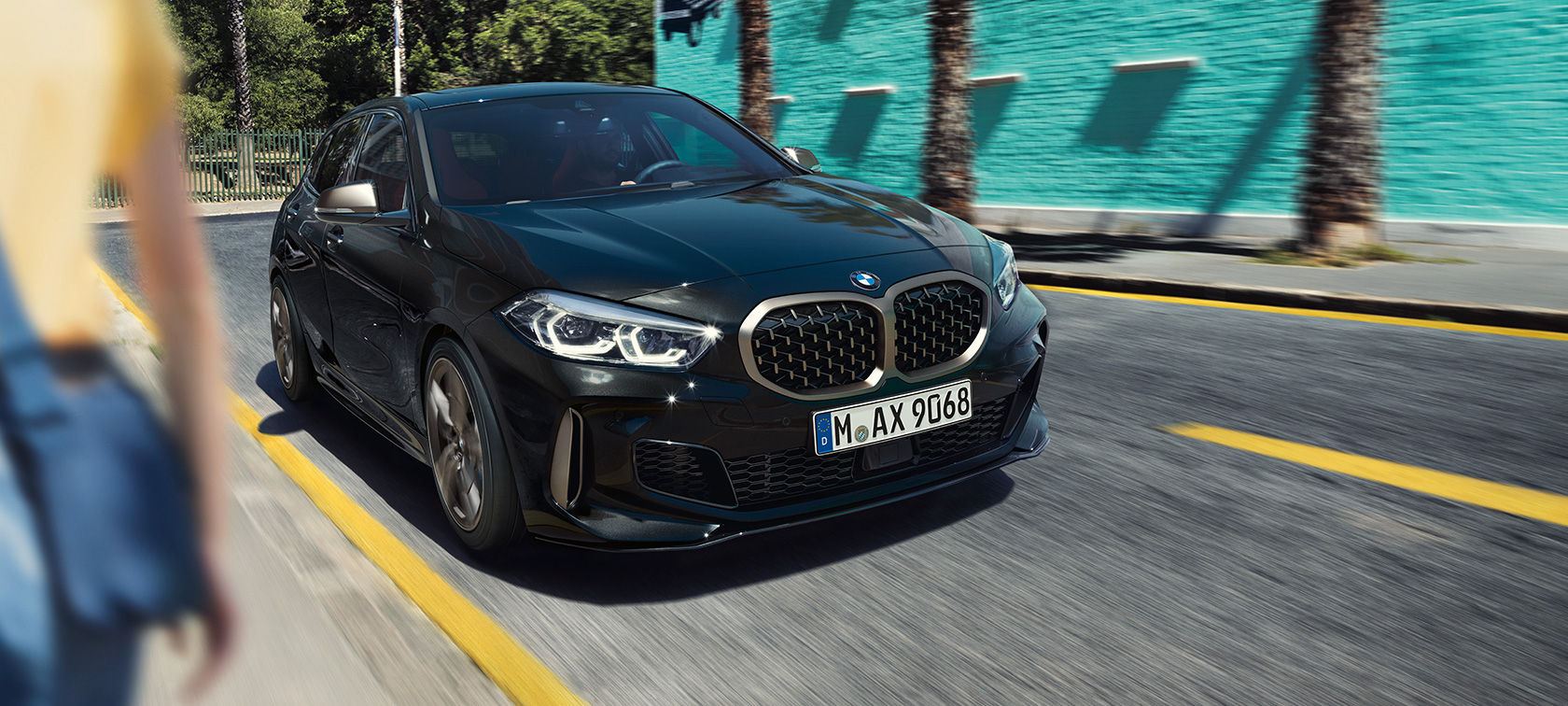 BMW M135i xDrive, three-quarter front view. BMW M135i xDrive in Black Sapphire metallic, three-quarter front view driving.
