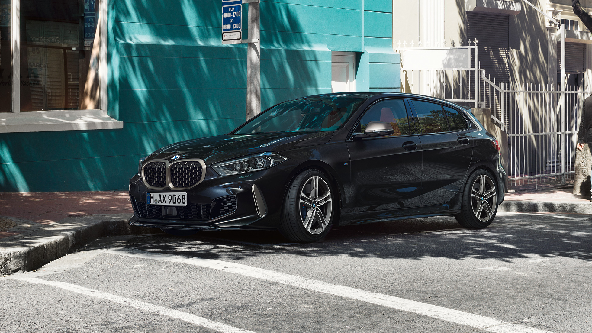 BMW M135i xDrive, three-quarter side view. The all-new BMW M135i xDrive in Black Sapphire metallic, three-quarter side view parking.