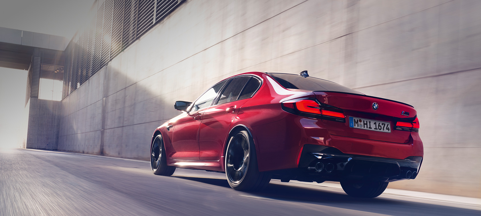 BMW M5 Competition F90 LCI Facelift 2020 three-quarter rear view driving BMW M5 Competition F90 LCI Facelift 2020 BMW Individual Imola Red three-quarter rear view driving
