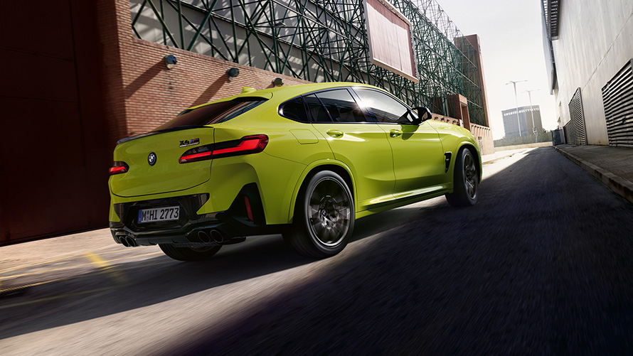 BMW X4 M Competition F98 LCI 2021 Three-quarter front view BMW X4 M Competition F98 LCI Facelift 2021 Sao Paulo Yellow three-quarter front view driving between factory buildings