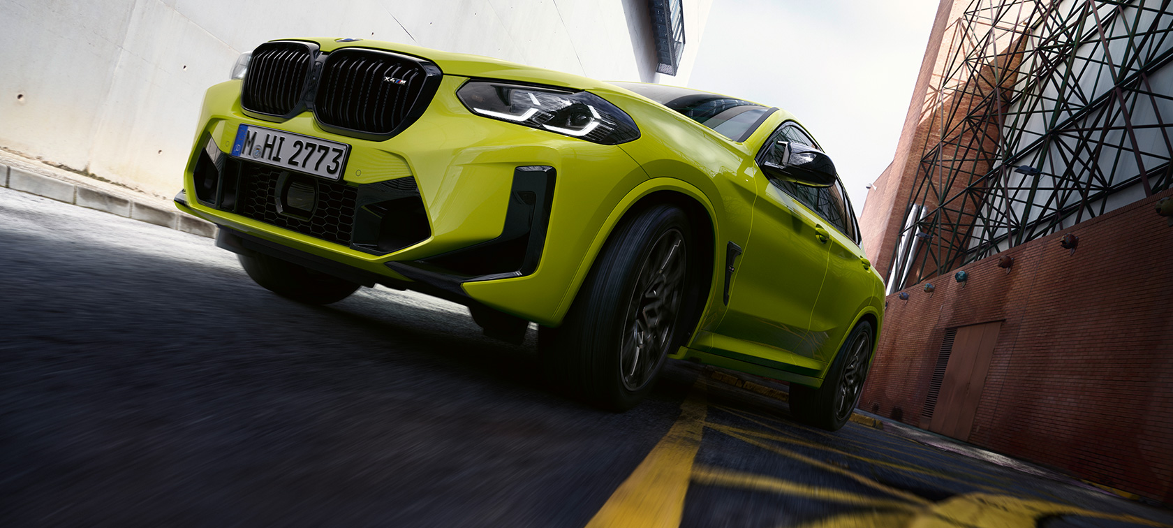 Three-quarter front view with bottom view BMW X4 M Competition F98 LCI 2021 BMW X4 M Competition F98 LCI Facelift 2021 Sao Paulo Yellow three-quarter front view with bottom view driving through a canyon of houses