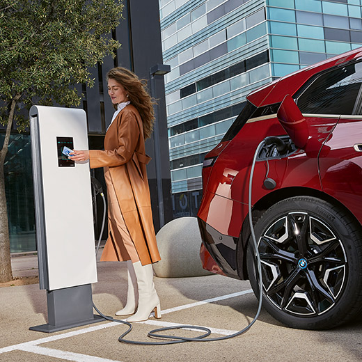 BMW iX i20 at charging station Woman with BMW Charging Card