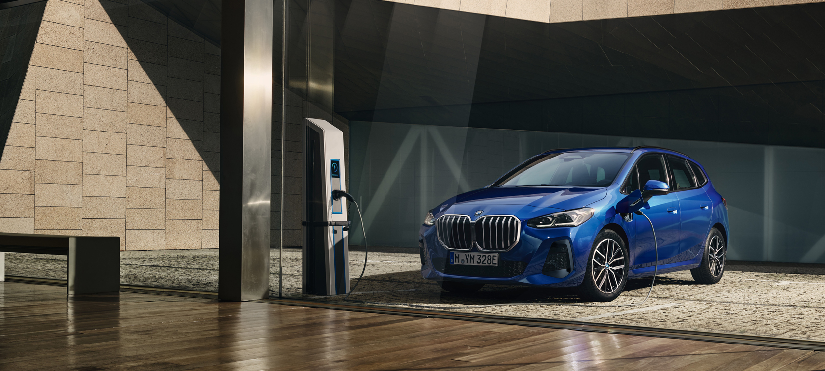 BMW 2 Series Active Tourer 230e plug-in hybrid U06 2021 M Portimao Blue metallic three-quarter front view at the charging station