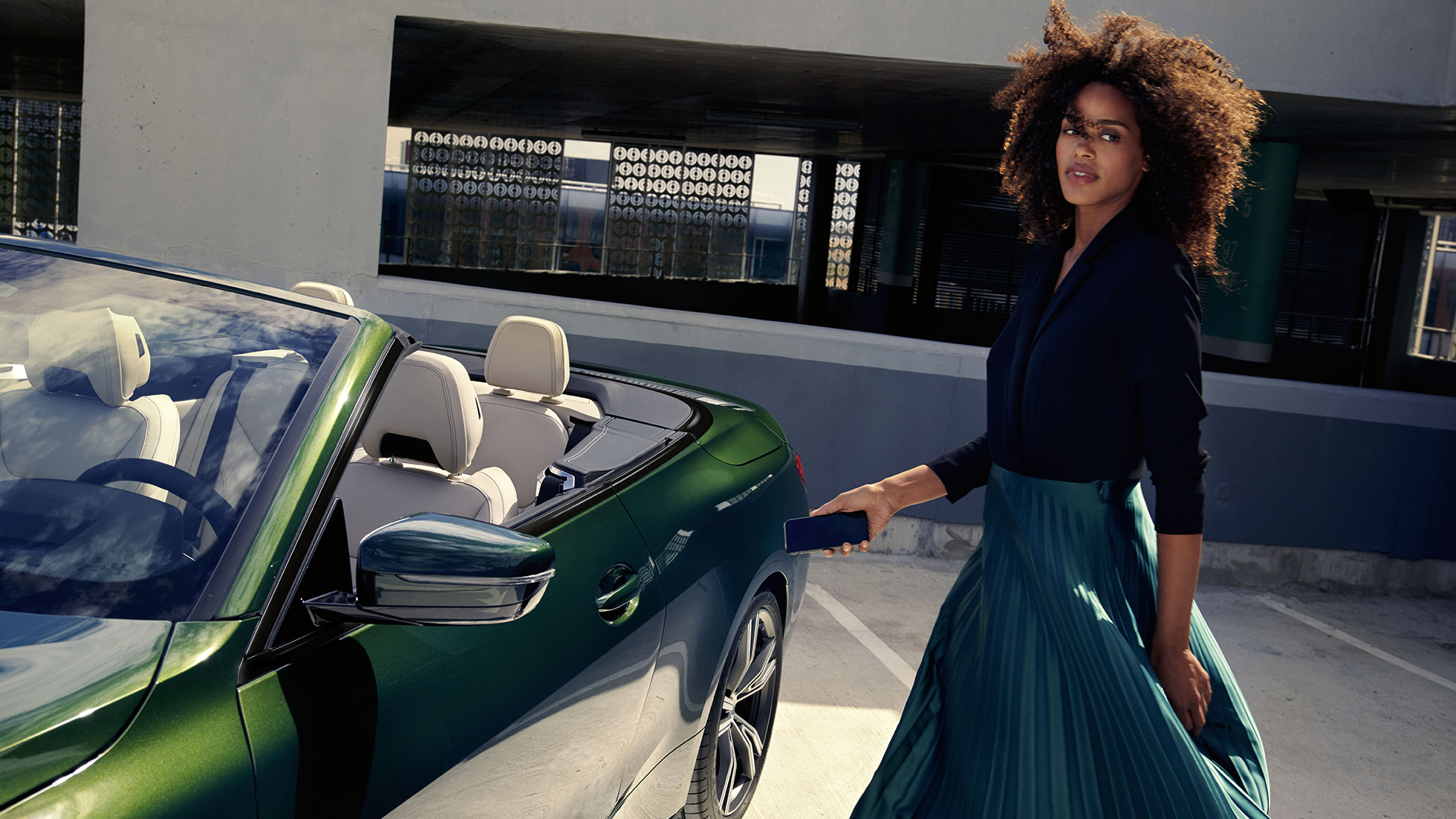 BMW 4 Series Convertible G23 2020 partial side view with a woman using digital key on smartphone BMW 4 Series Convertible G23 2020 San Remo Green metallic partial side view with a woman using digital key on smartphone