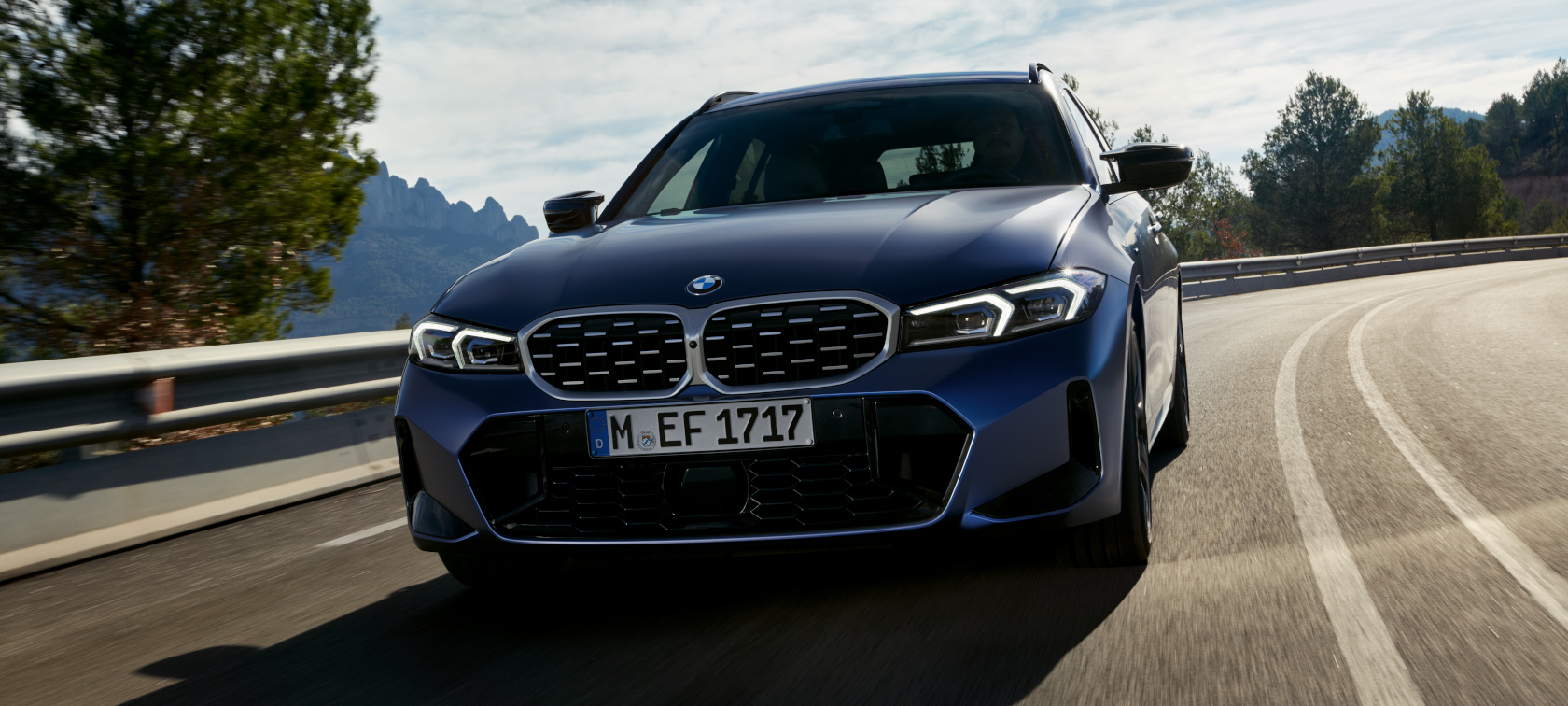 BMW M340i xDrive Touring G21 front view driving on the street BMW M340i xDrive Touring G21 Frozen Tanzanite Blue front view driving on the street