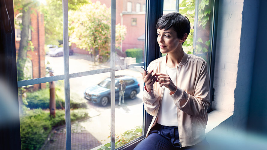 BMW Connected app Woman by window using BMW Service Share Live Trip Status