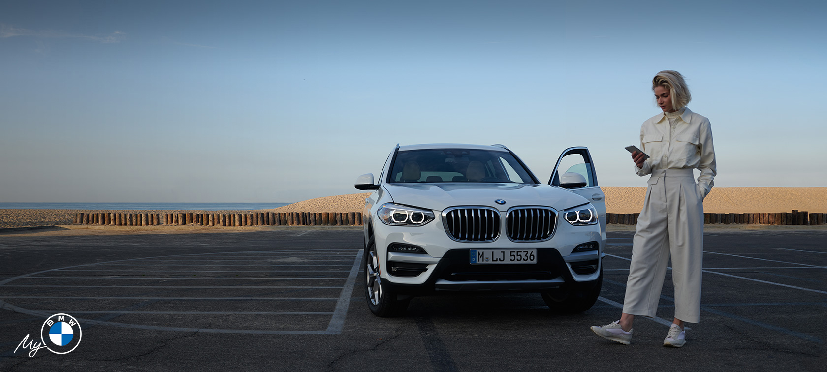 Woman using My BMW app in front of BMW. Woman using My BMW app in front of BMW.