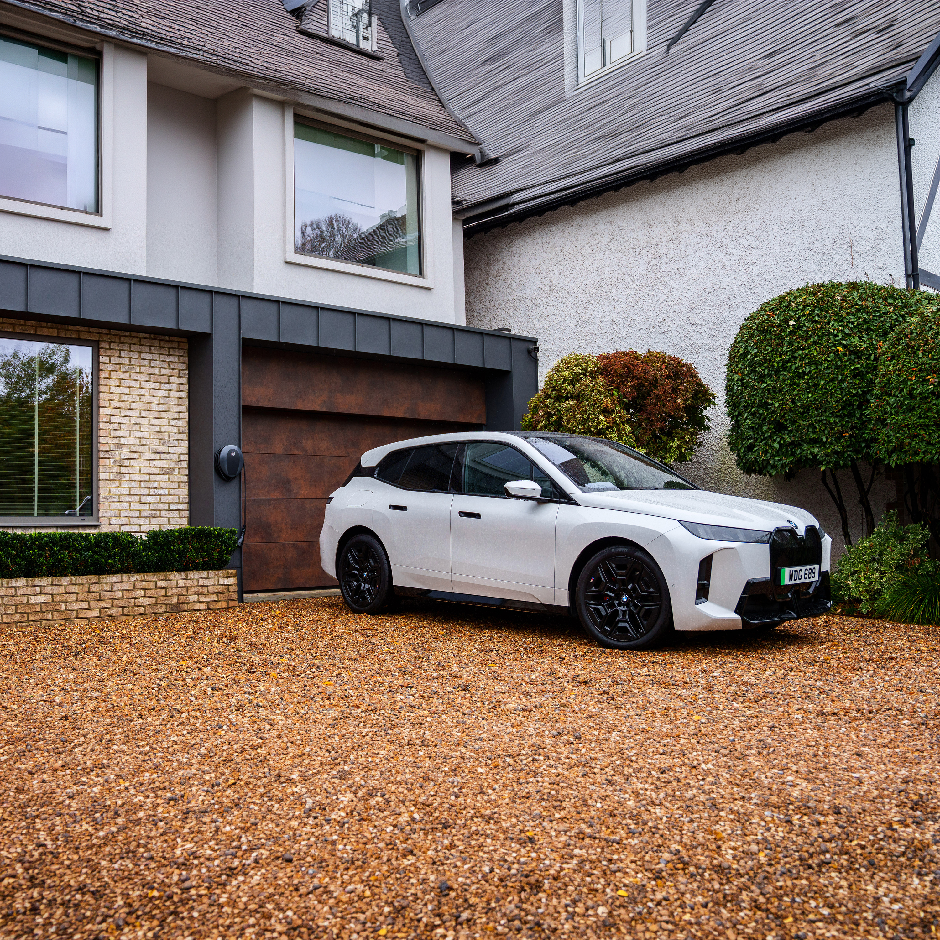 A woman is walking towards a BMW iX3 connected to a wallbox